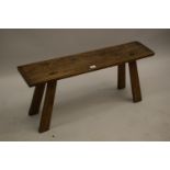 Small primitive 19th Century elm bench, the chip carved and gouge moulded plank top above four splay