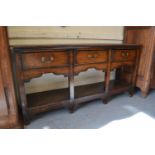 Small George III oak dresser base, the moulded top above three drawers with brass swan neck handles,