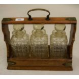 Late Victorian oak three bottle tantalus with plated mounts