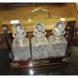 Reproduction mahogany and brass mounted three bottle tantalus with cut glass decanters