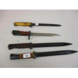 Three various bayonets with black and steel blades, together with another with composition grip