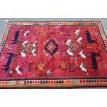 Tibetan rug with animal and bird designs on a rose ground with borders, 5ft 8ins x 4ft approximately
