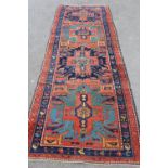 Antique Kazak runner with a repeating medallion design on a brick red field with borders,