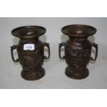 Pair of oriental bronze two handled vases decorated in high relief with figures of birds, 8ins high