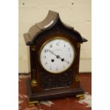 Edwardian mahogany mantel clock, the shaped arch top case with flanking quarter pilasters and carved