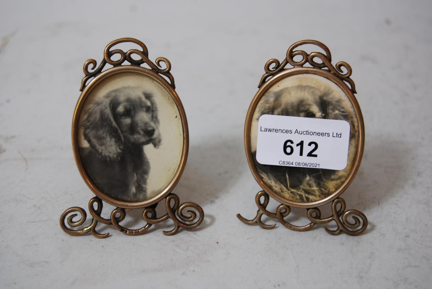 Pair of miniature silver gilt oval photograph frames with integral back stands on scroll supports,