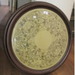 Floral needlework panel worked with silver and gilt thread in a moulded wooden circular frame, 24ins