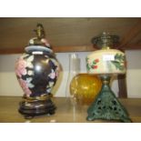 Oil lamp with coloured glass well and green painted iron stand together with a modern table lamp
