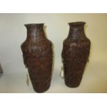 Pair of carved bamboo vases decorated with figures and buildings in a landscape, having mask head