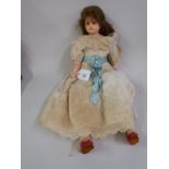 Wax shoulder plate doll with fixed eyes and wax limbs wearing a white lace trimmed gown with blue