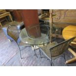 Circular glass garden table with painted wrought iron base together with four matching chairs with