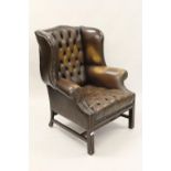20th Century brown leather button upholstered wing arm chair, raised on mahogany reeded front