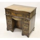 Small reproduction mahogany serpentine fronted kneehole desk, the moulded crossbanded top above a