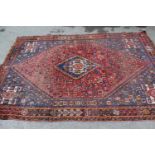 Shiraz rug with a medallion and all over stylised floral design on a red ground, with corner designs