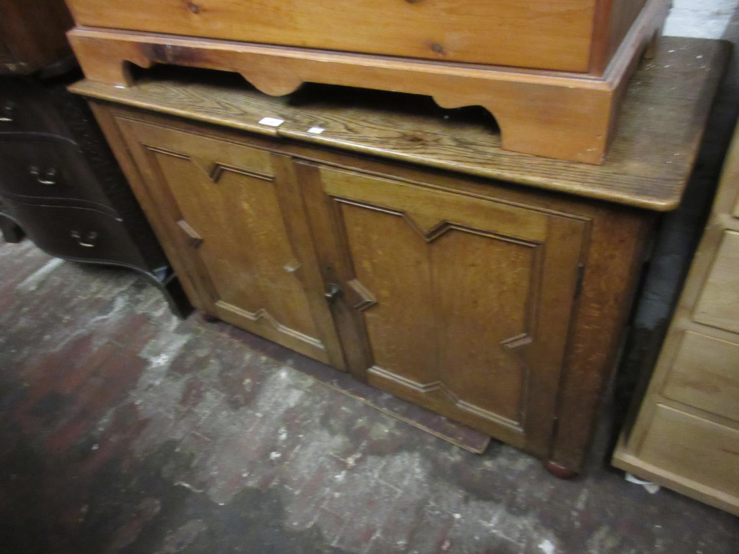 Oak side cabinet with two geometrically moulded panel doors on later bun feet, with a hinged top (