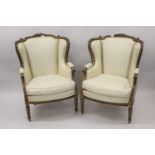 Pair of 19th Century French carved giltwood wing arm salon chairs upholstered in a striped cream