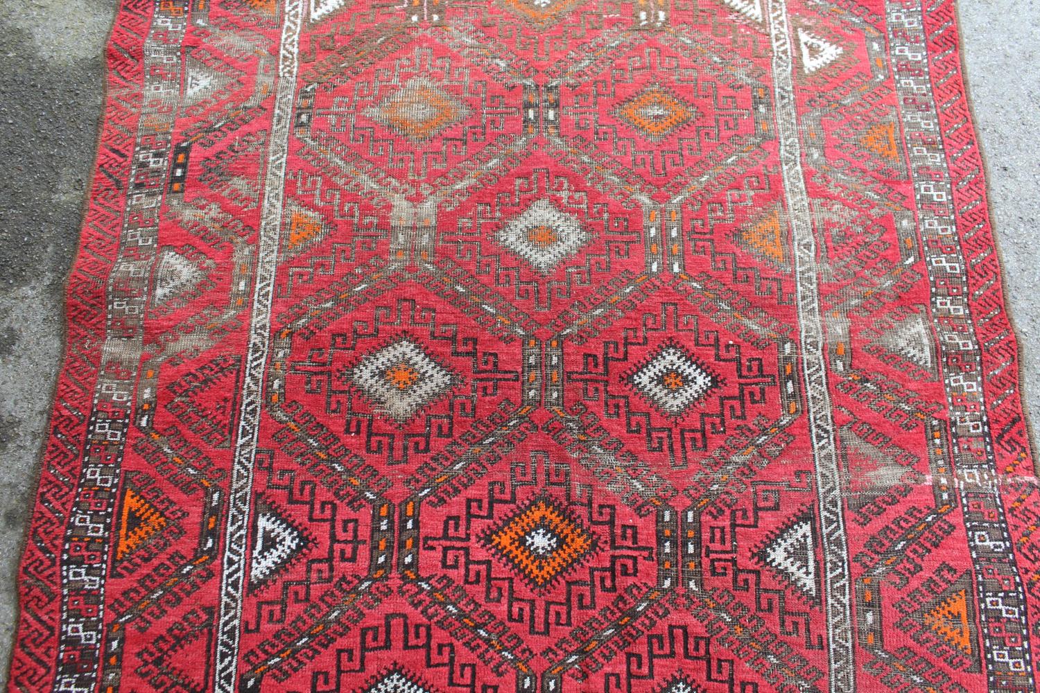 Afghan rug with a repeating hooked medallion design on a wine red ground with borders (some wear), - Image 3 of 4