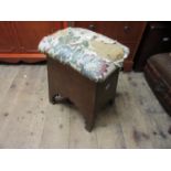 Arts and Crafts Liberty type oak stool, the padded seat above tapering sides with arched friezes and