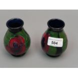 Pair of small modern Moorcroft baluster form vases with tube lined flower decoration on a dark