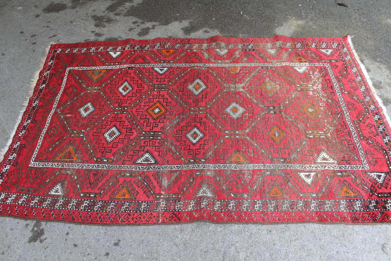 Afghan rug with a repeating hooked medallion design on a wine red ground with borders (some wear),