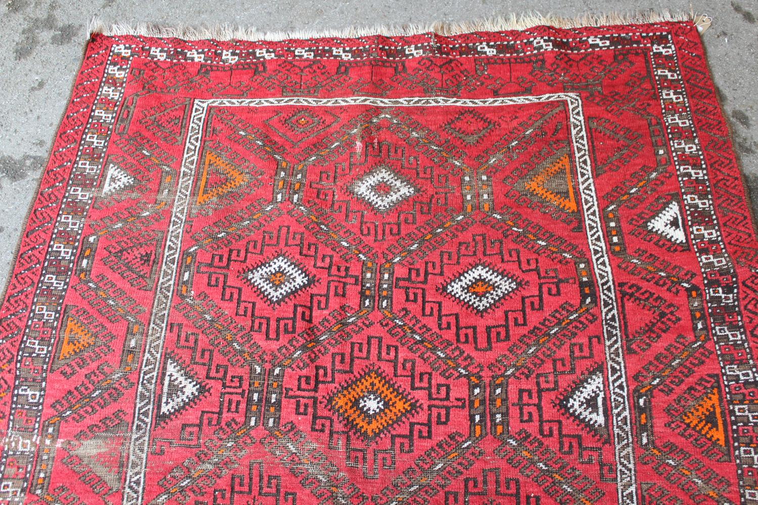 Afghan rug with a repeating hooked medallion design on a wine red ground with borders (some wear), - Image 2 of 4