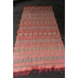 Sumak runner of geometric pattern on a red ground, 99ins x 44ins together with a similar smaller