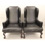 Pair of large black leather upholstered wing armchairs on shell carved cabriole claw and ball