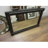 Early 20th Century ebonised rectangular wall mirror with bobbin decorated frame, 32ins x 20ins