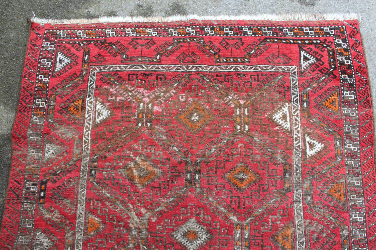 Afghan rug with a repeating hooked medallion design on a wine red ground with borders (some wear), - Image 4 of 4