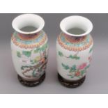 Pair of 20th Century Chinese baluster form vases decorated with exotic birds, on hardwood stands,
