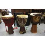 Three large African skin covered drums in zip carrying cases, together with a folding chrome and