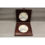 Two circular blue and white decorative wall plaques mounted in square wooden oriental frames, 9.5ins