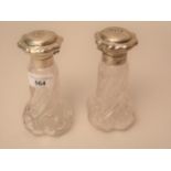 Pair of silver mounted glass perfume bottles, the covers embossed with lily of the valley