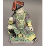 Small late 19th / early 20th Century Chinese famille verte figure of a seated immortal wearing a