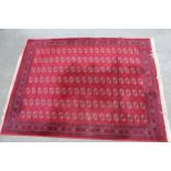 Machine woven carpet of Turkoman design with seven rows of gols on a red ground with borders, 12ft x