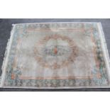 Chinese carpet with a central oval floral medallion on a beige ground with borders, 12ft x 9ft