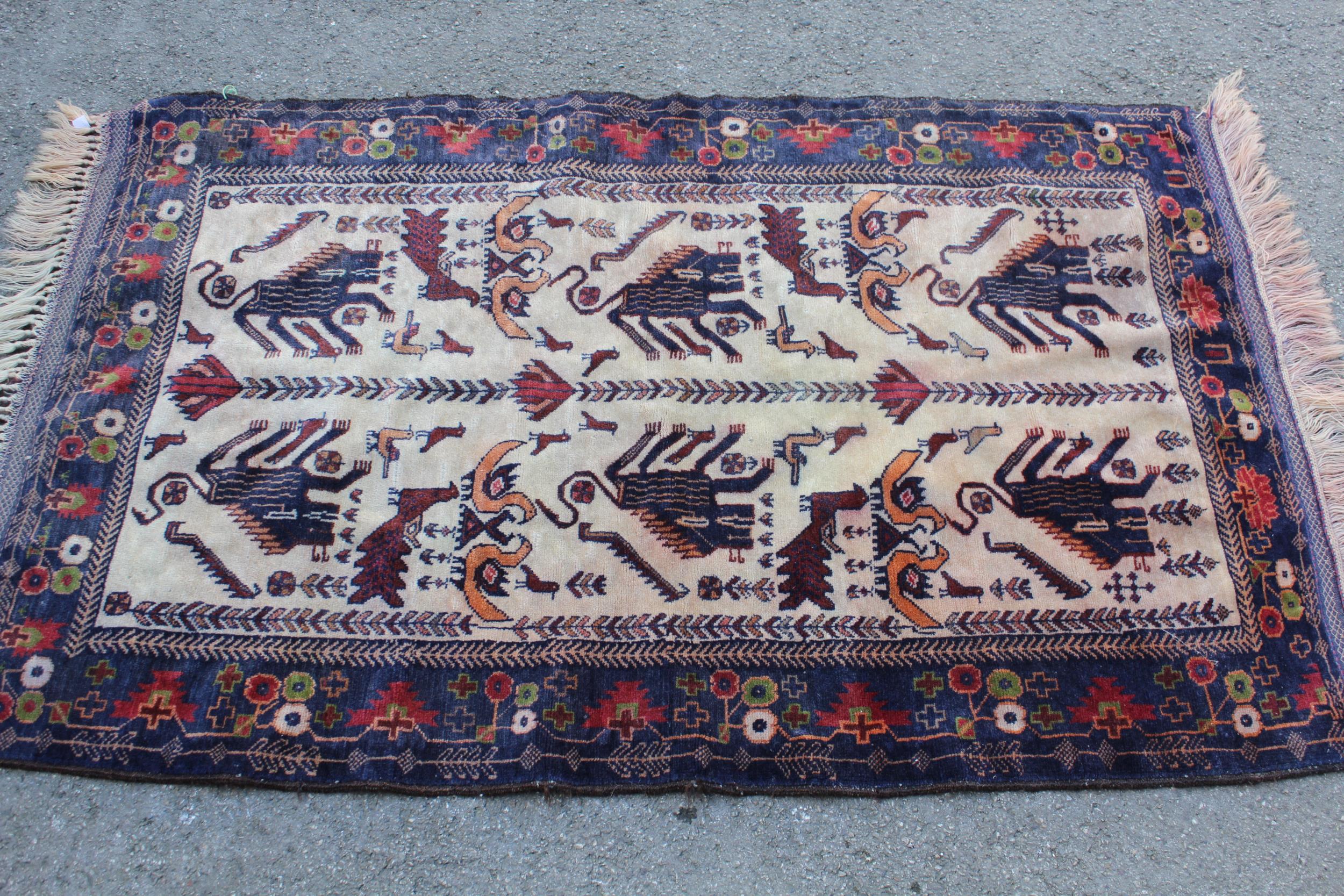 Small modern Belouch rug with animal and bird design on an ivory ground with borders, 4ft 10ins x