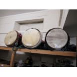Three large African skin covered drums in zip carrying cases, together with a folding chrome and