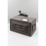 19th Century Irish bog oak tea caddy, the hinged cover surmounted by a figure of a dog, 9ins wide