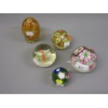Four various glass paperweights and an amber glass egg on a brass mount