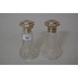 Pair of silver mounted glass perfume bottles, the covers embossed with lily of the valley