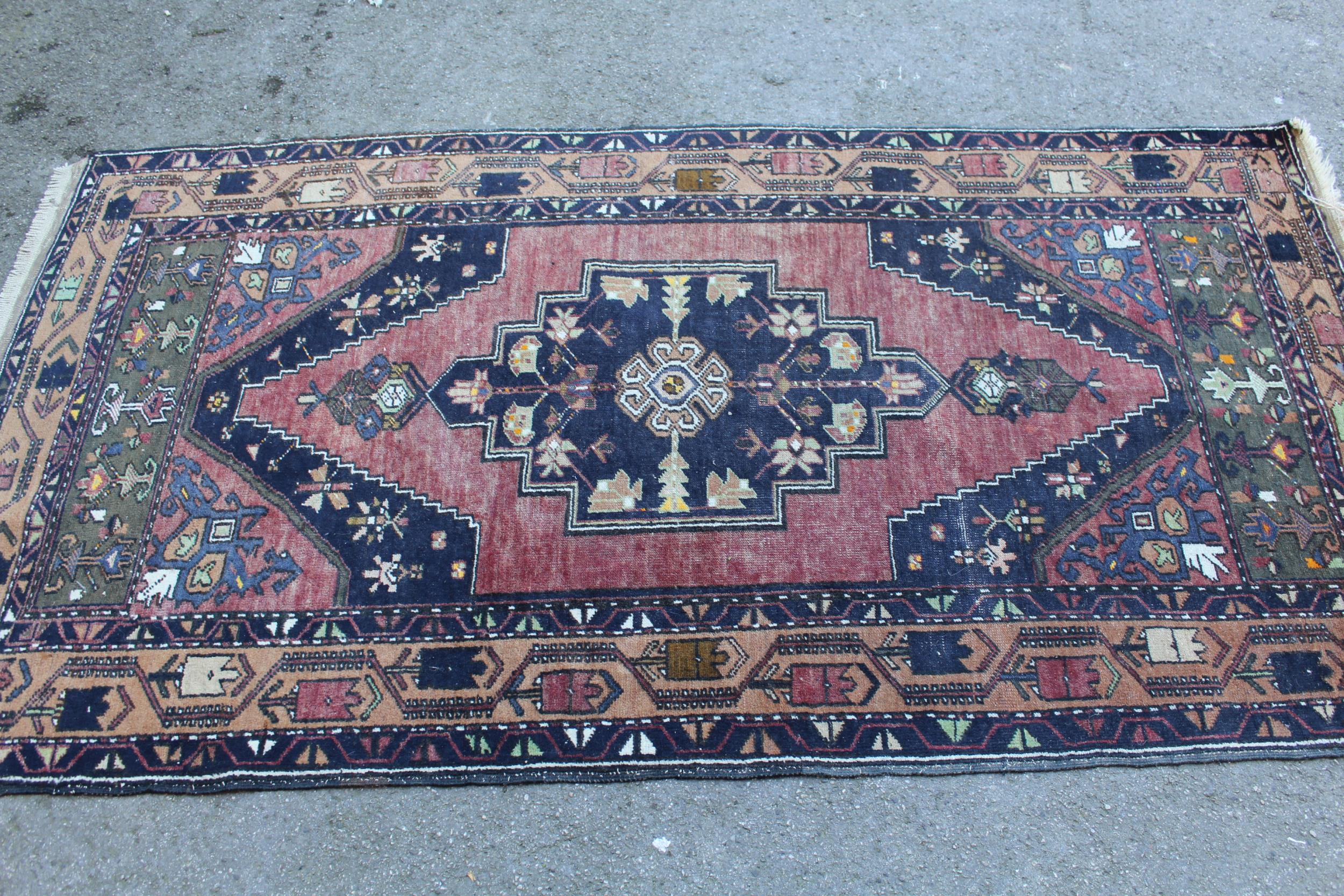 Kurdish rug with centre medallion and all-over floral design on a dark red ground with borders,