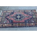 Kurdish rug with centre medallion and all-over floral design on a dark red ground with borders,