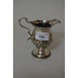 George III silver pedestal cream jug with a gadroon rim, scroll handle and floral embossed body,