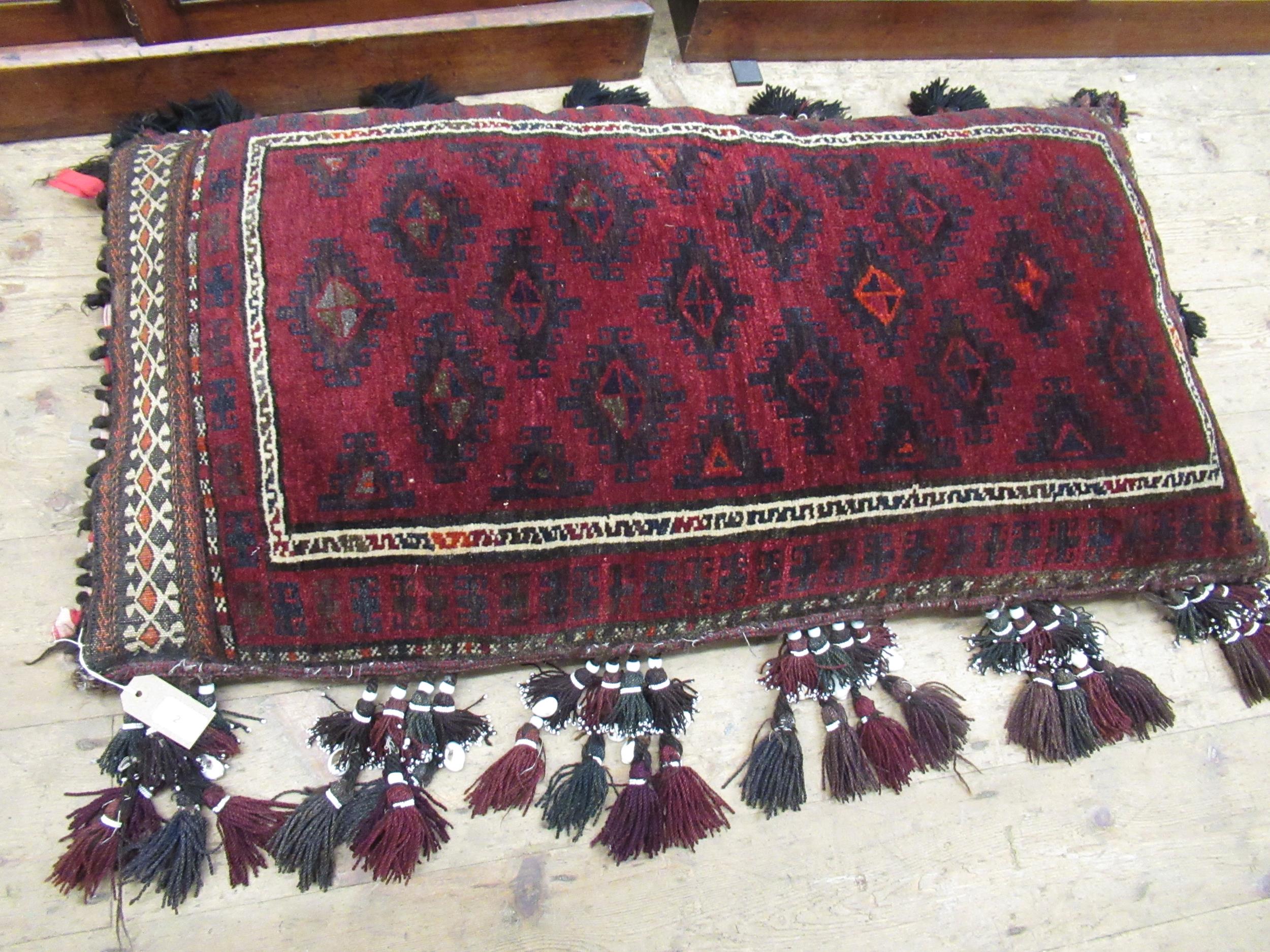 Afghan carpet fragment covered floor cushion with bead and shell work tassels, 24ins x 44ins