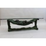 20th Century patinated bronze coffee table in the form of a child in a hammock with glass top,