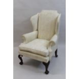 20th Century wing back armchair having cream damask upholstery with loose cushion, raised on