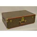 Vintage Louis Vuitton suitcase with brass catches and corner mounts, the hinged lid enclosing a void