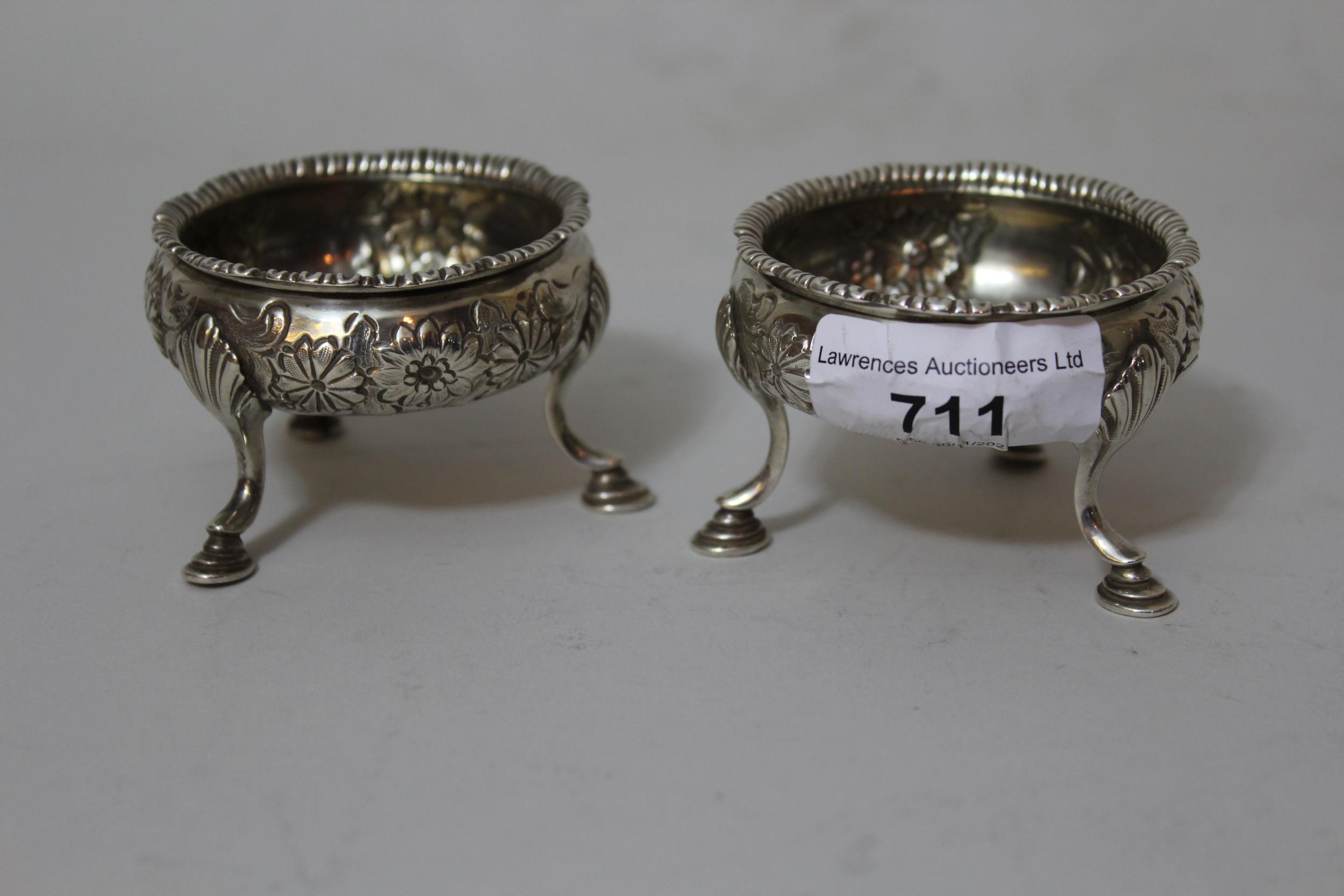 Pair of London silver floral embossed salts on hoof supports, maker Hester Bateman