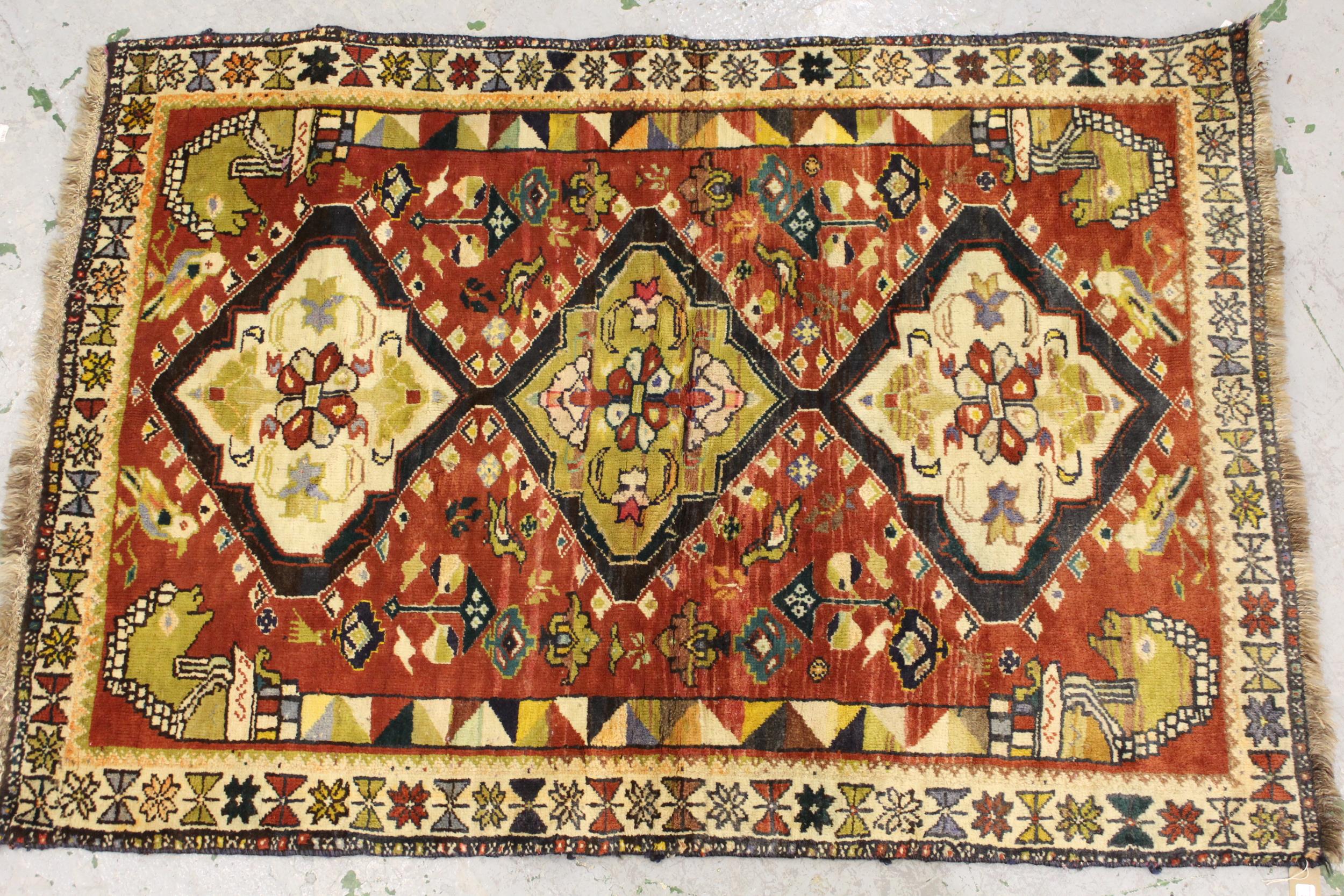 Kurdish rug with a triple pole medallion design on rose ground, with all over further stylised